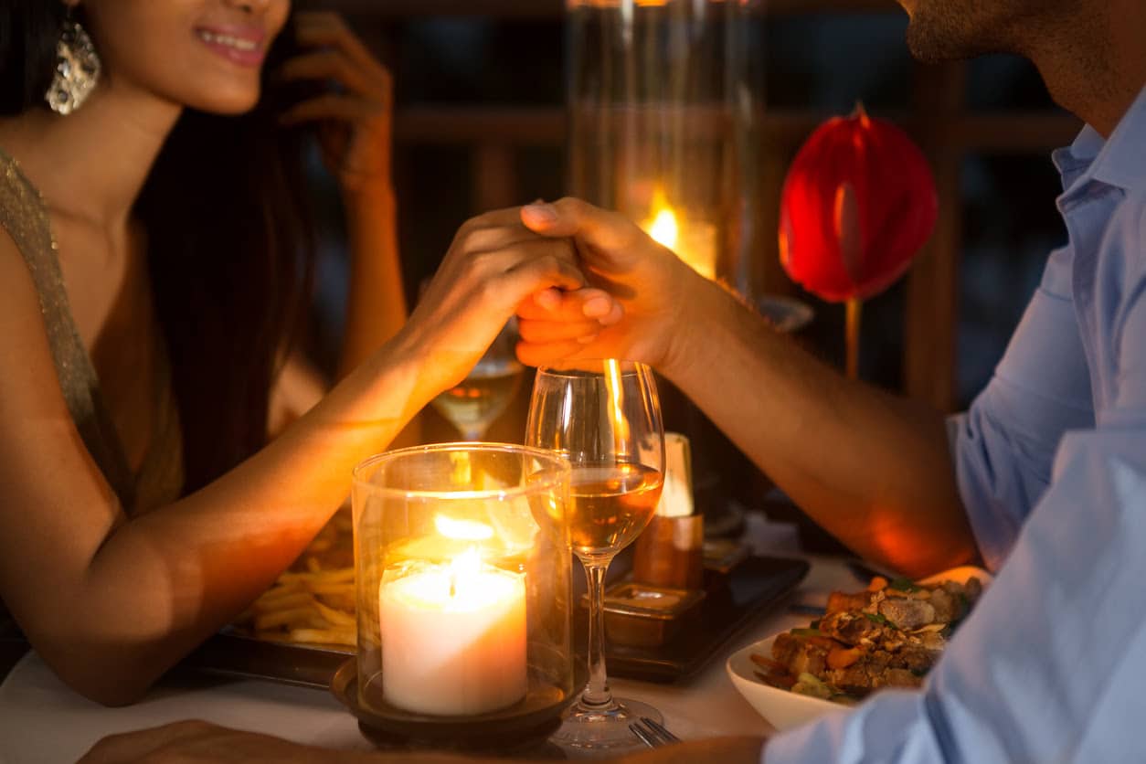 Vegas Restaurants Romantic couple holding hands together over candlelight during romantic dinner.